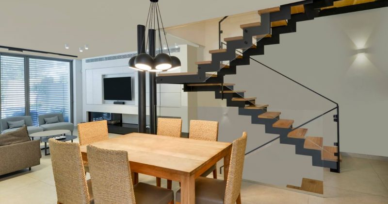 מדרגות עץ וברזל שחור עולים למעלה וחולפים על פני פינת האוכל הביתית